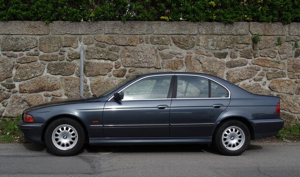 BMW E39 5 Series sedan parked by stone wall