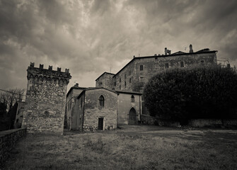 Fototapeta premium VIew of Frosini medieval Tuscan village features an ancient stone watchtower with Guelph battlements and historical fortified buildings nestled among green hills