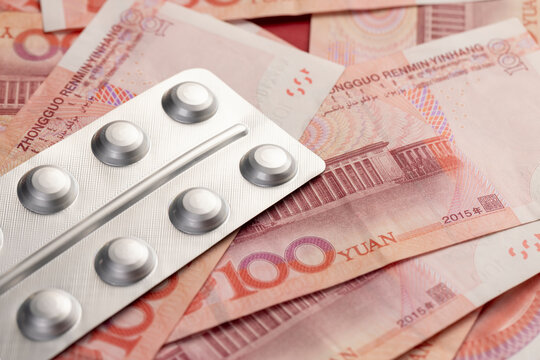 Chinese cash for one hundred yuan and pills in a packaged blister, medicines and Chinese cash with a face value of 100 yuan are lying together.