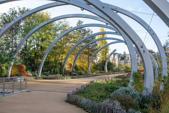 Walkway passes through arches in a park garden landscape in daylight autumn in Promenade de la Rose de Cherbourg Paris La Defense France