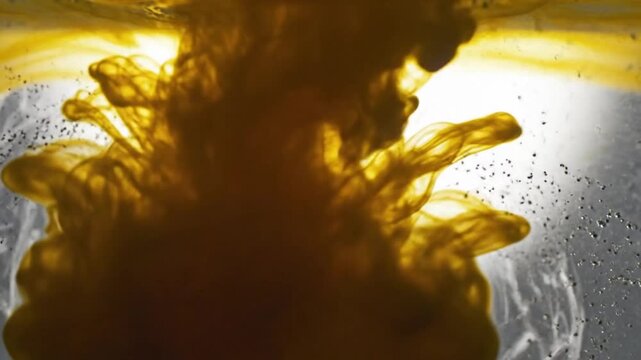 Abstract ink diffusion in water forming a beautiful organic golden shape with small particles in suspension