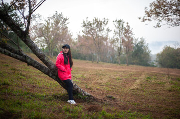 Fototapeta premium A woman in a pink dress stands in the middle of a forest with cherry blossom trees.