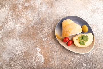 Smoked Mozzarella cheese, with tomatoes and olives on brown concrete, top view, copy space.