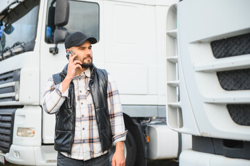 Fototapeta premium Truck driver talking on phone beside big rig