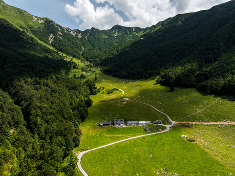 Mountain refuge, Casera Coot, Natural Julian Alps Park, nestled in a green valley, surrounded by forested slopes under a partly cloudy sky. Casera Canin,Resia Valley,Julian Alps,Italy