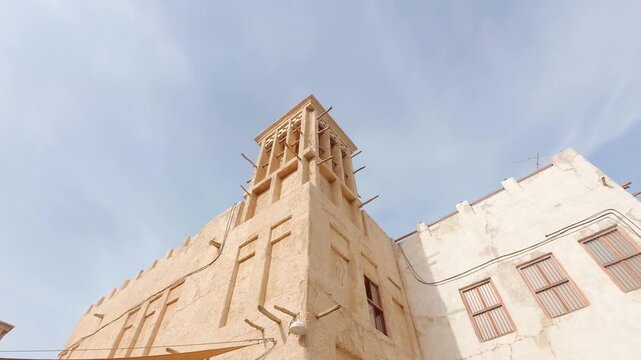 Dubai, UAE - 25th january, 2026: Old Dubai wind tower architecture overlooking creek heritage district timelapse transition clouds daylight traditional urban skyline