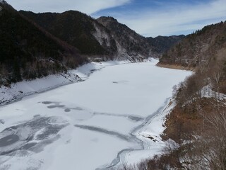A frozen river with snow-covered trees in the background. The scene is calm and tranquil, with the frozen water reflecting the surrounding landscape. The snow-covered trees add a sense of stillness
