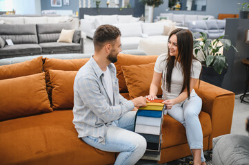 Young couple choosing sofa fabric in furniture store