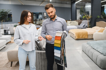 Obraz premium Woman choosing fabric swatches with sales consultant in furniture store