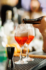 Fototapeta premium Pouring orange cocktail into glasses