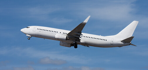 Airplane take off on the blue sky, with white clouds. Aircraft flying on sky background. White passenger jet plane in the blue sky. Low angle view of Airplane flying under blue sky, with white clouds
