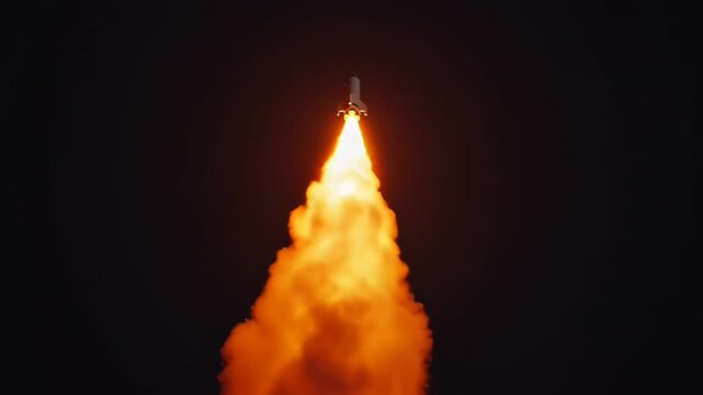 Nighttime rocket launch with blazing exhaust plume soaring into dark sky.