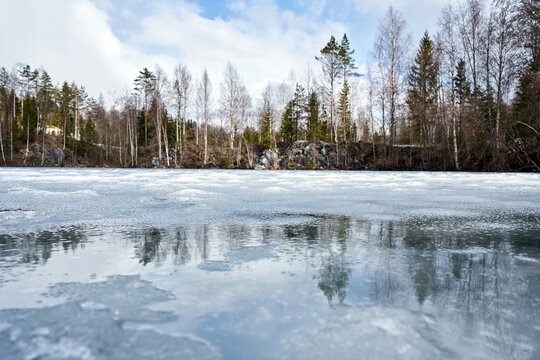 Frozen lake surface with forest reflected, showcasing a winter and early spring nature landscape. Outdoor scene, seasonal environment.