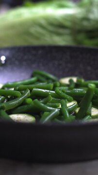 Vertical video. I pour vegetables into a frying pan. Vegetables in a frying pan. Cooking dinner.