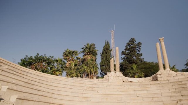 Panning low-angle view of ancient stone amphitheater ruins with preserved seating tiers and columns. Roman amphitheatre in Kom el-Dikka archaeological site, Alexandria, Egypt