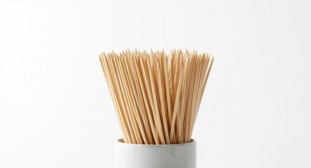 Container of bamboo toothpicks standing neatly arranged on a bright white background