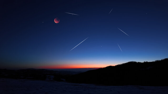Blue hour time with lunar eclipse, stars and planets above landscape silhouettes.