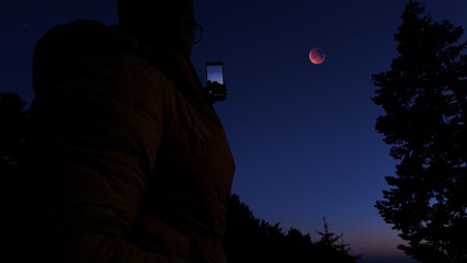 Fototapeta premium Amateur astronomer with smartphone photographing and observing stars, planets, Moon and other celestial objects.