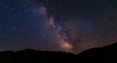 Fototapeta premium Celestial scene displaying vibrant constellations in a starry night with mountainous silhouettes and significant copy space