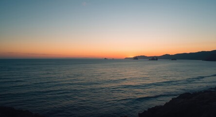Naklejka premium Evening coastal panorama showing serene ocean and glowing horizon