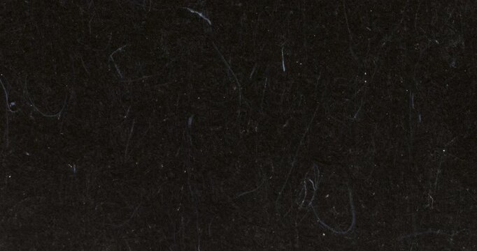 Abstract stop-motion video of dark black felt or wool fabric texture with visible fibers and dust specks. Useful as a moody background, loop, or design overlay.