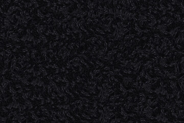 Dark black curly sheep wool texture background, close-up of natural fluffy lamb fur textile material