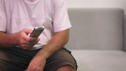 Chill Multitasking Scene, Man Relaxing With Devices, Person On Sofa Comfortably Using Phone And Television Remote, Individual Reclines On Couch Juggling Messaging And Entertainment With Ease