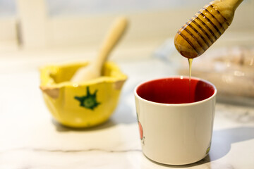 Honey dripping from wooden dipper into cup, natural and healthy food concept