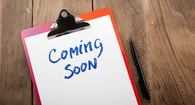 Close up of colorful clipboard and blank paper with coming soon handwritten phrase and marker on rough wooden backdrop