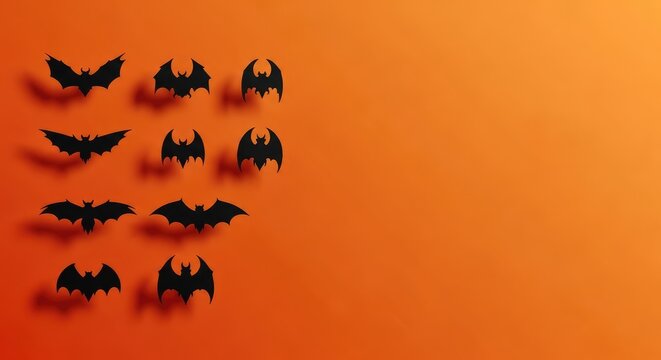 Black paper bats against vibrant orange background with shadows creating halloween themed design with space for text spooky minimalist