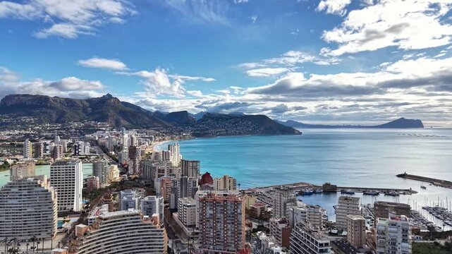 sunlit coastal skyline overlooking azure bay, highrise buildings and busy marina, shimmering water and clear