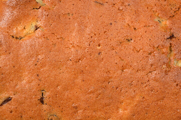 A high resolution macro shot of a golden brown baked sponge cake surface showing porous texture and small crumbs
