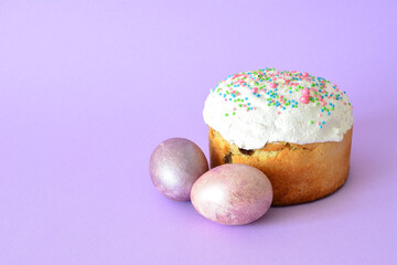 traditional Easter Kulich with colorful Sprinkles and Pastel Eggs on lilac backdrop