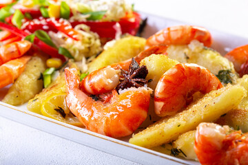 Cooked shrimp served with potatoes, vegetables and spices, seafood main dish with colorful garnish.
