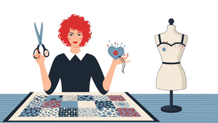 Woman with red hair is holding scissors and a pin cushion while standing behind a table with a patchwork quilt and a mannequin.