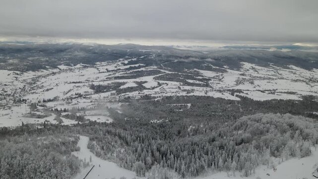 Mountains with snow-covered pine trees in winter. Panoramic aerial drone view. Ski or snowboard  resort in winter. Ukraine, Carpathians, Play. Aerial panoramic drone view from above, top view from dro