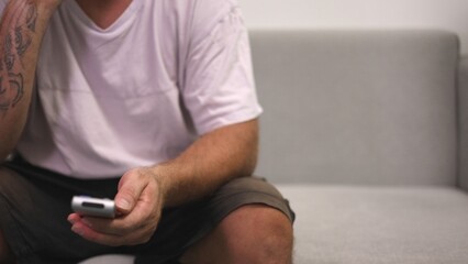 Male Delivery Man Pauses Messaging, Male Delivery Worker Relaxes While Casually Communicating During Break, Adult Male Courier Seated Comfortably On Sofa During Brief Resting And Messaging Session
