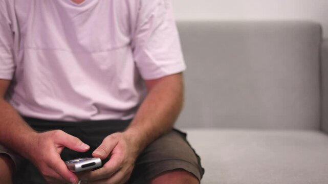 Individual Irritated Due To Repeated Attempts With Faulty Remote Control, Person Experiencing Frustration From Constantly Pressing Buttons On Wornout Remote Control In Comfortable Home Setting