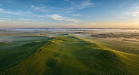 Obraz premium Golf course panorama with smooth hills during early dawn from the air
