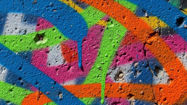 Vibrant graffiti adorns a weathered concrete wall with abstract shapes and colors from a close-up view