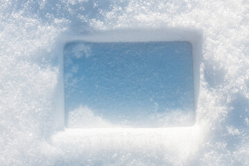 Rectangular imprint on the fluffy, snowy surface with sunlight.
