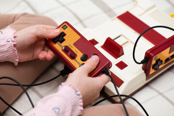 Retro gamepads in a girl's hands, closeup. Nostalgia for the 80s and 90s.