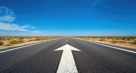 Asphalt road arrow marking showing traffic direction facing clear horizon under vibrant blue sky