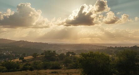 Fototapeta premium Bright sunlight emerging from cumulus clouds casting warm glow on wild terrain