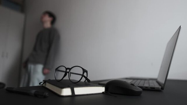 Depressed man standing by wall in home office covering face with hand, illustrating mental fatigue and freelance burnout