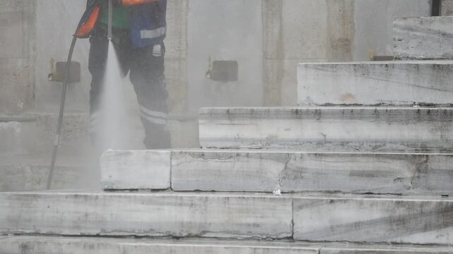 Worker pressure washing stone stairs outdoors daylight footage