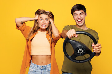 Naklejka na ściany i meble Young fearful couple two friends family man woman wear casual clothes look camera hold head steering wheel driving car together isolated on pastel plain light yellow color background studio portrait.