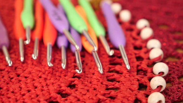 Set of colorful crochet hooks on red handmade lace doily with white beads and sparkles