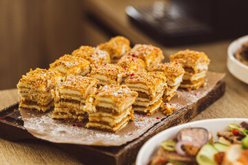 Sliced layered honey cake with cream and powdered sugar