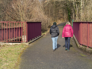 Deux personnes de dos de passage sur un pont en for&ecirc;t